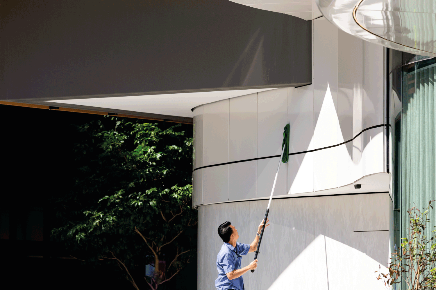 worker using sponge on a long pole to clean wall