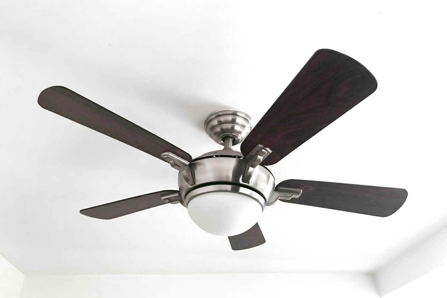 A ceiling fan with gray blades inside a white ceiling room