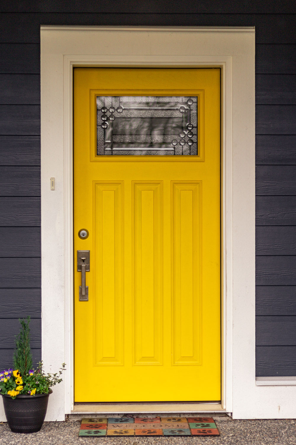 A front door with dark purple painted sidings and a yellow front door with white trims