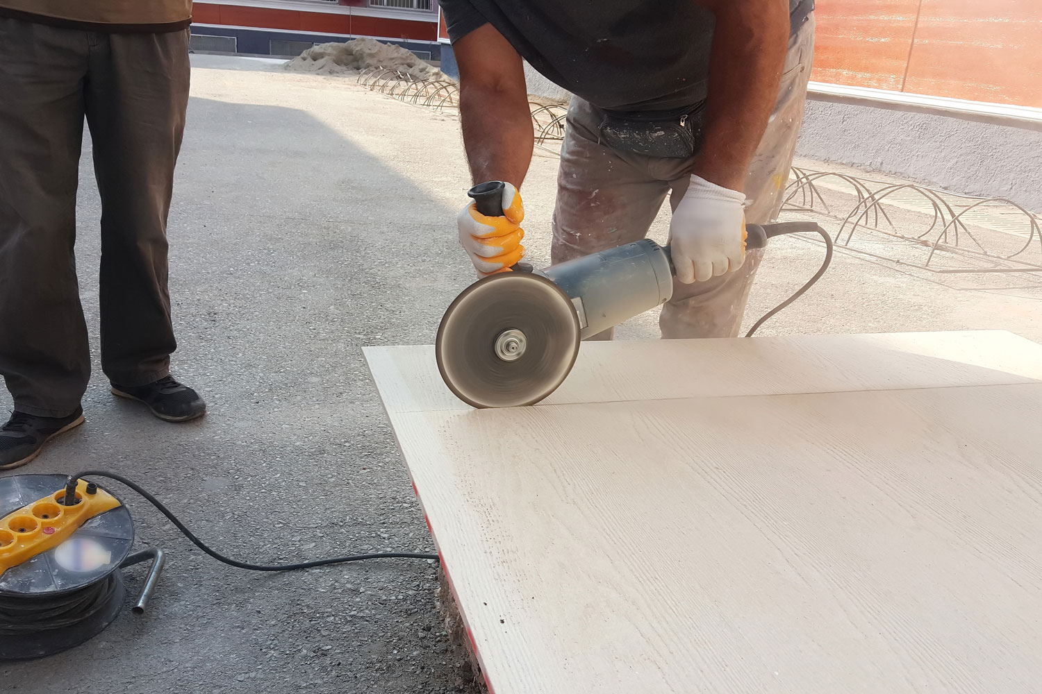 A properly equipped worker using a sanding disk to cut the gypsum board
