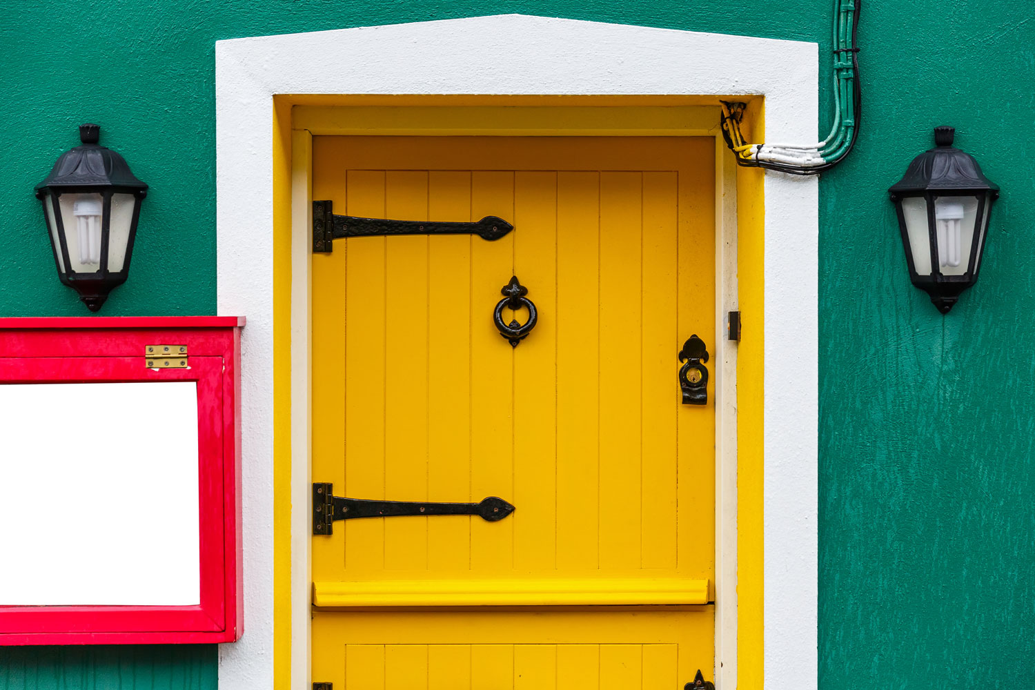 A yellow colored front door with white trims and green painted facade