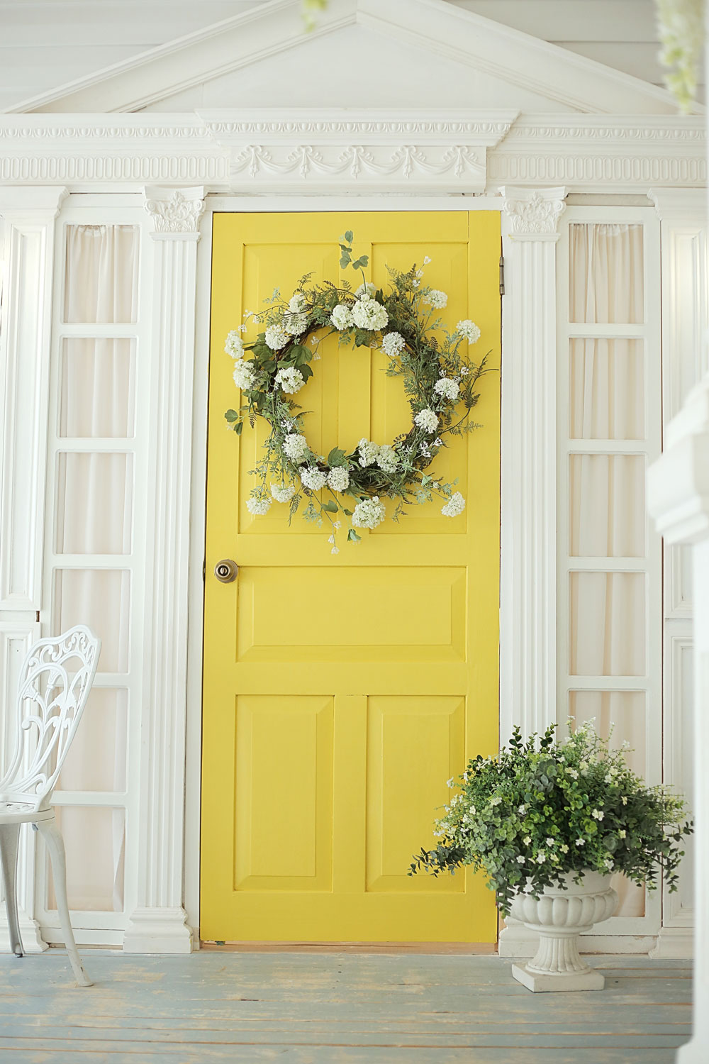 A yellow front door with a flower wreath for decoration