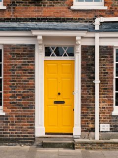 A yellow front door with white trims and a brick facade, What Does A Yellow Front Door Mean?