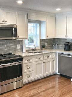 Classic and luxurious modern kitchen with white cabinets, silver cabinet handles and kitchen appliances, What To Put In The Cabinet Above Your Fridge [Ideas Explored]