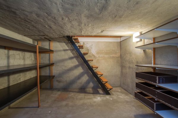Empty basement in abandoned old industrial building with little light and a wooden stairs and cement walls