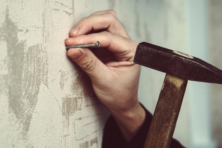 Guy hammering a nail in a plaster wall, What Are The Best Nails For Plaster Walls?
