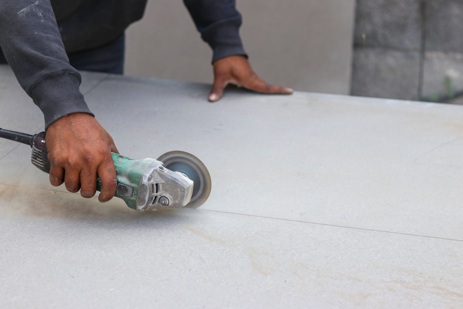 Worker using a cutting disk on the cement board