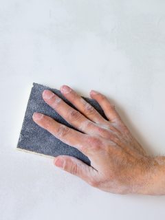 plastering man hand sanding the plaster in white wall - What Grit Sandpaper For Drywall