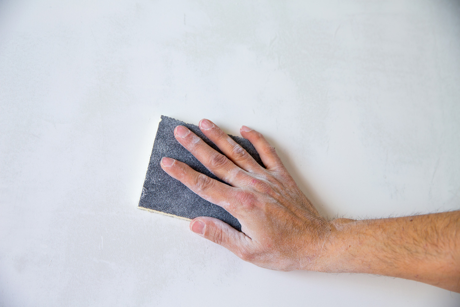 plastering man hand sanding the plaster in white wall
