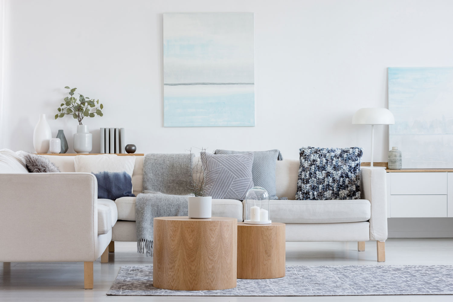 A fabric sectional with gray and blue throw pillows with wooden coffee tables