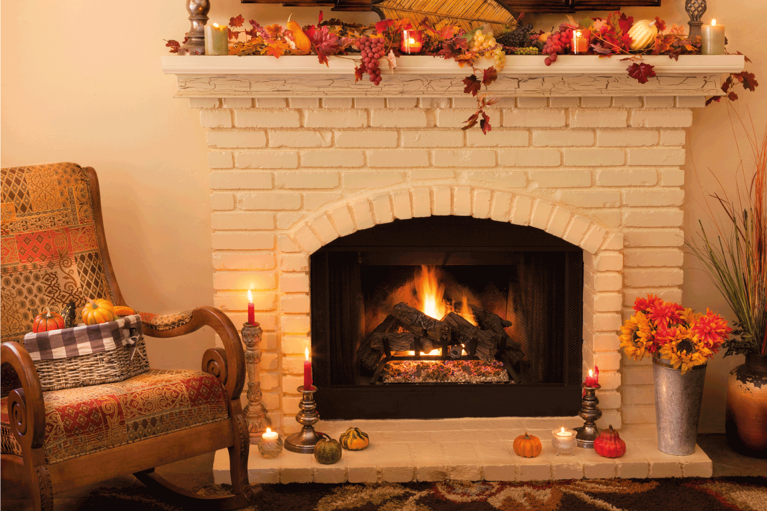 A light yellow brick old fashioned fireplace with arched opening has a roaring fire with logs and is decorated on the mantel and hearth