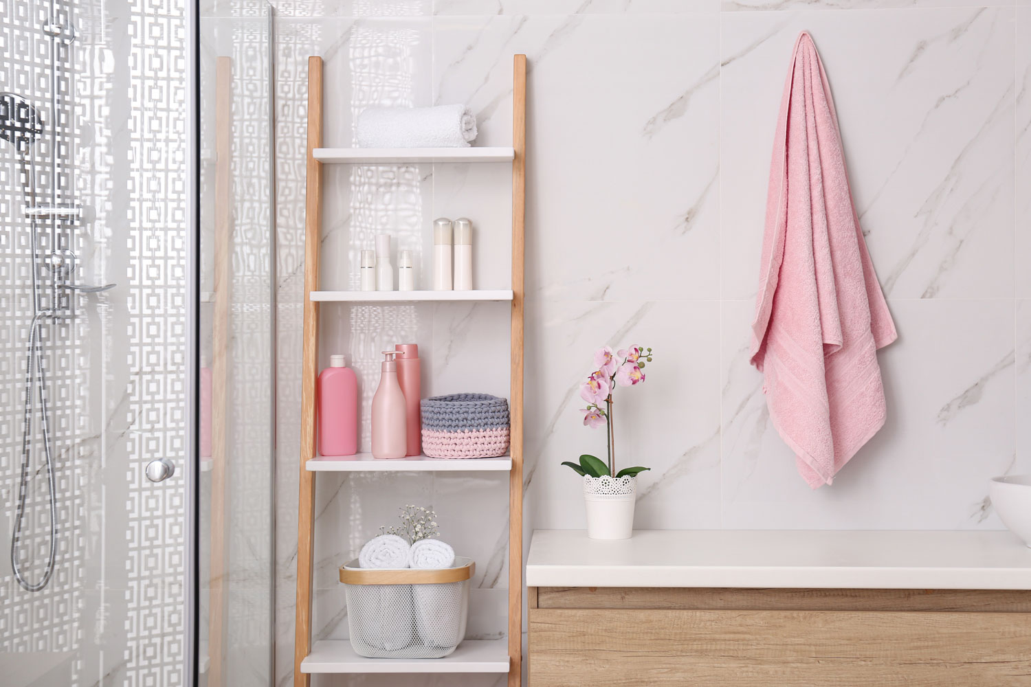 A pink towel hanged inside a boho themed bathroom with a ladder divider