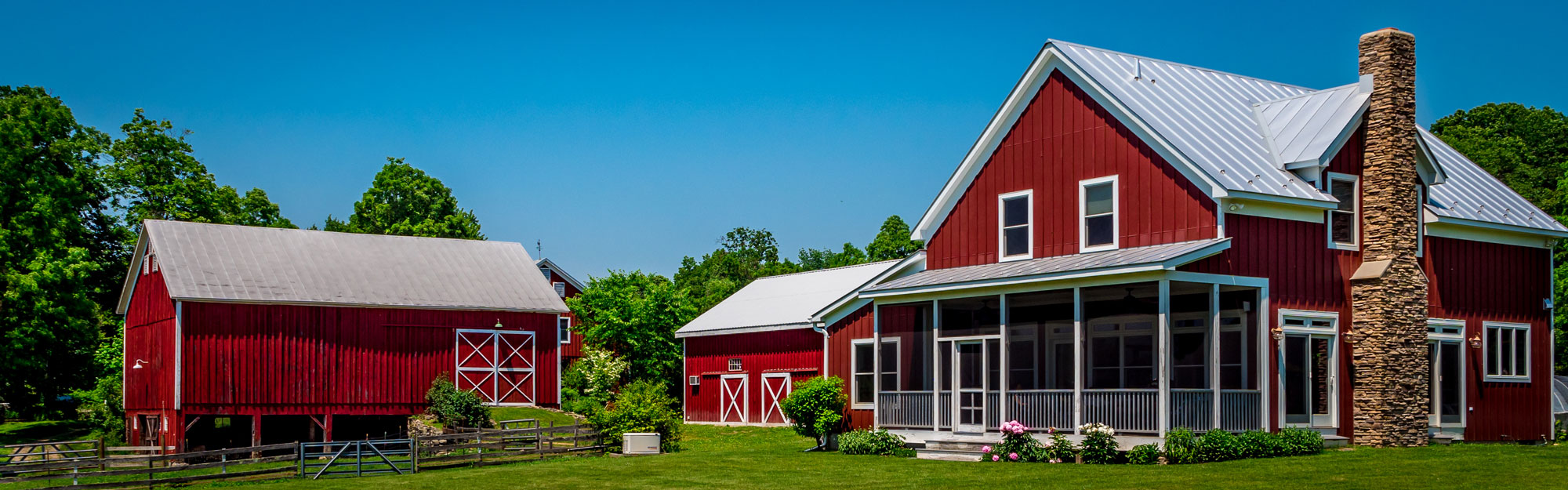 A spacious red farm area with red painted wooden sidings and white trims