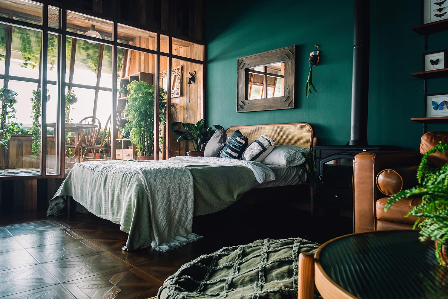 A stylish loft bedroom interior with brown coloured rattan furniture and wooden elements with dark green coloured wall