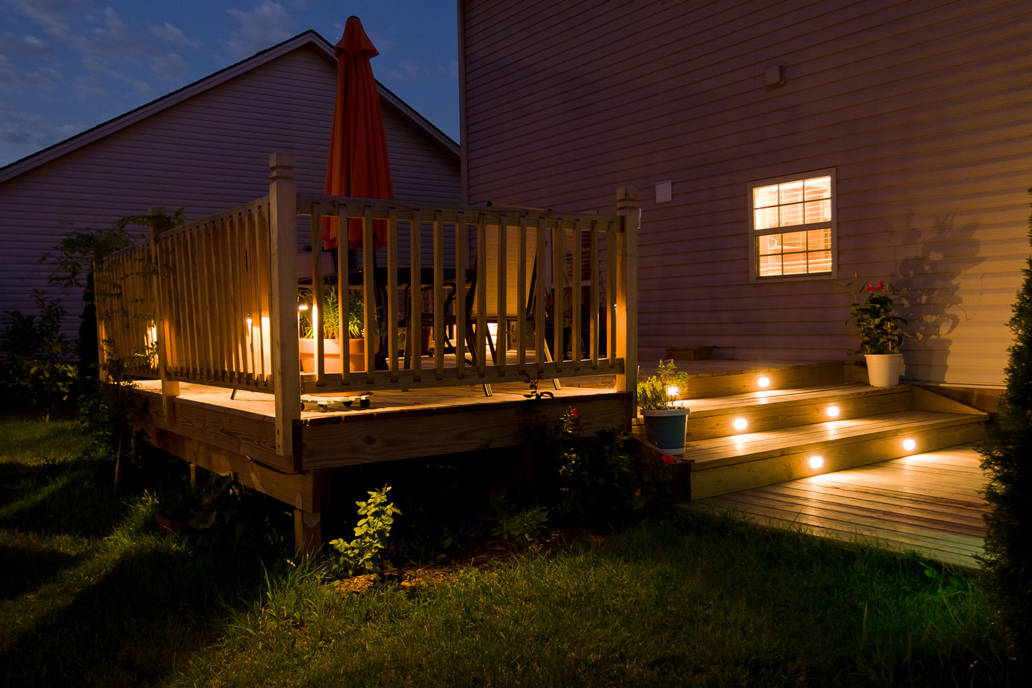 A wooden deck with proper lighting on the side and the stairs