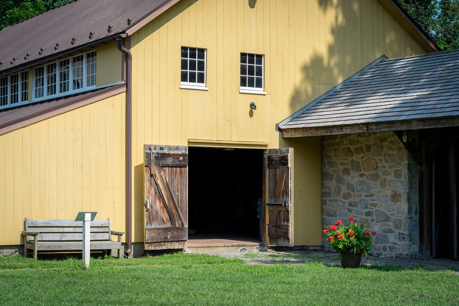 A yellow painted wooden siding barn house with opened wooden doors