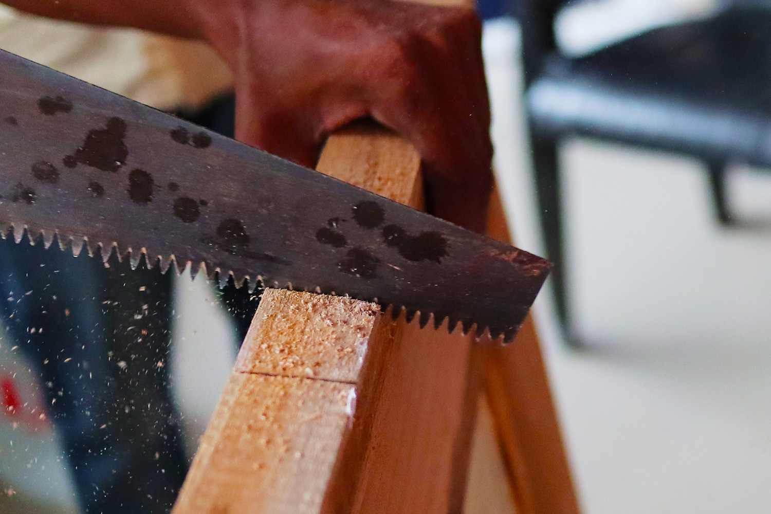 An wooden door being cut by a saw manually.