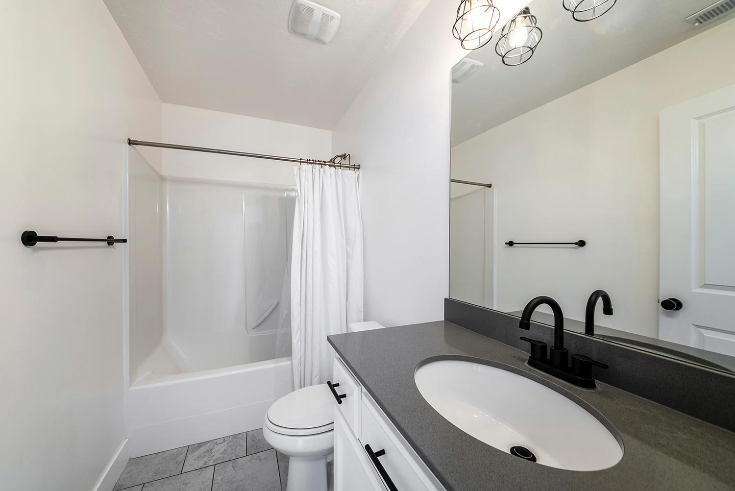 Bathroom interior with black fixtures and one piece shower tub with white shower curtain