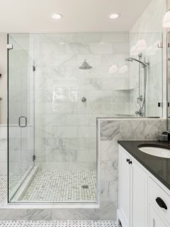 Beautiful master bathroom with shower, bathtub, and sink, with high end furnishings, lights on - Can You Use Floor Tile On Shower Walls