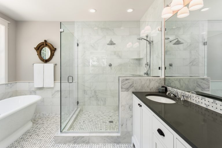 Beautiful master bathroom with shower, bathtub, and sink, with high end furnishings, lights on - Can You Use Floor Tile On Shower Walls