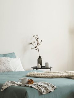 Bedroom interior with sage green and white sheets and cushions and a blanket, What Color Bedding Goes With Sage Green Walls?