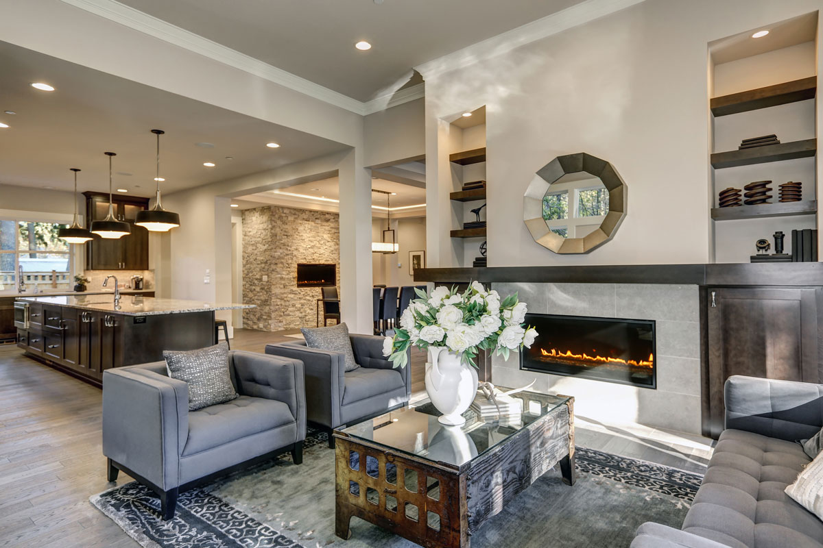 Chic living room filled with built-in cabinets flanking round mirror atop grey tile fireplace