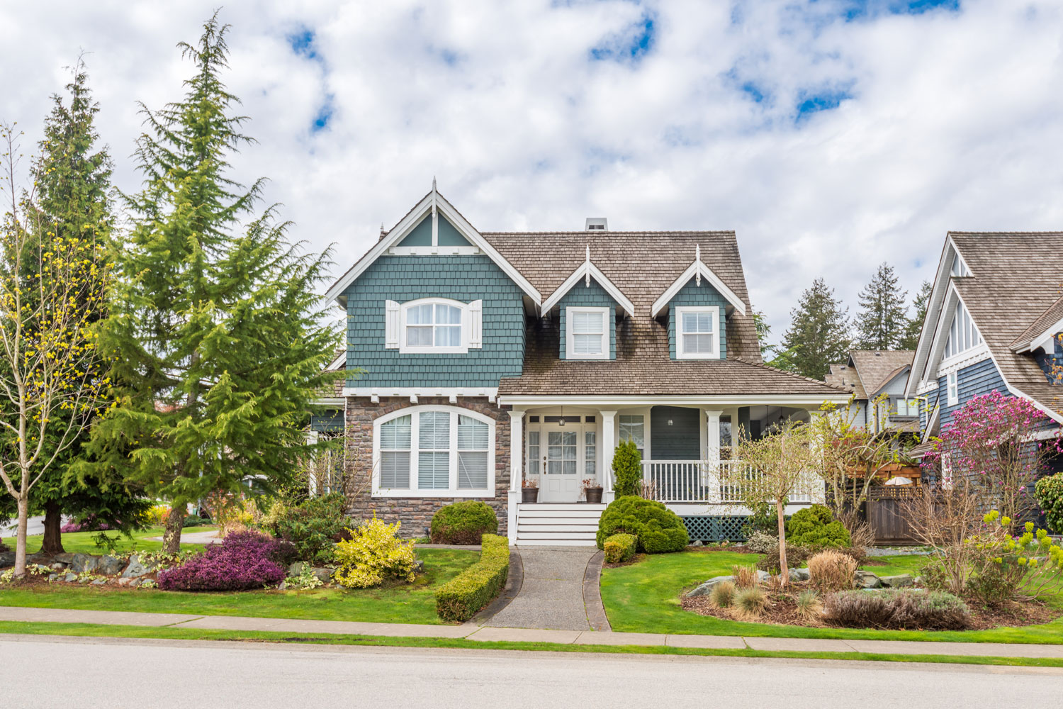 Classic two story designed house with blue shingle sidings and beautiful landscaping