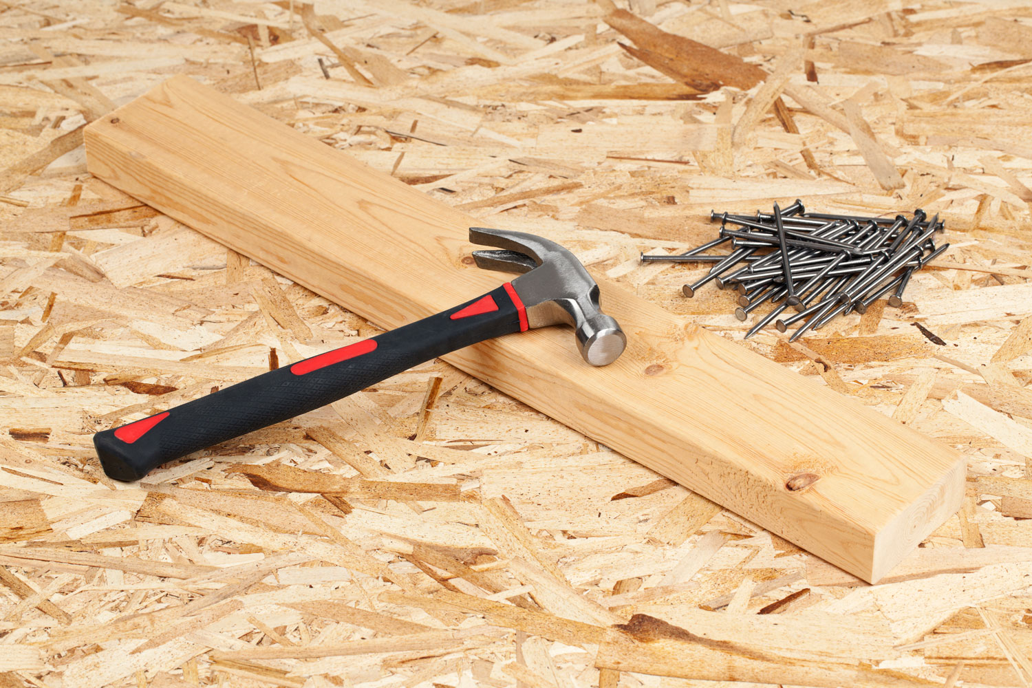 Hammer and nails with a wooden plank on the side at a construction site