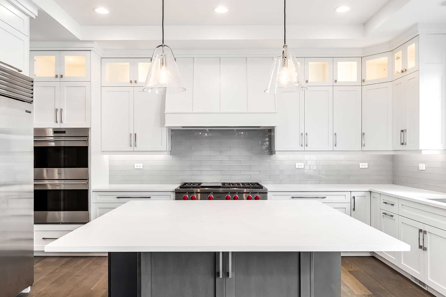 Kitchen cabinets with white countertop black handles and tile backsplash