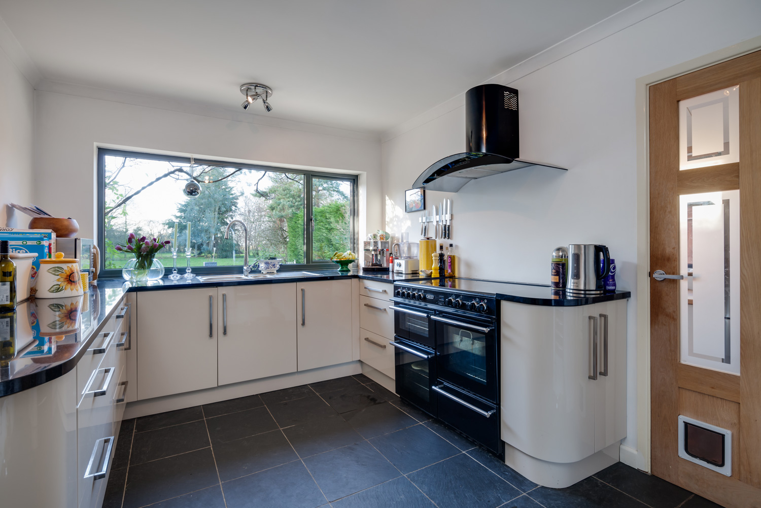  Kitchen with fitted cabinets, granite worktops, black range style oven and bright white walls.