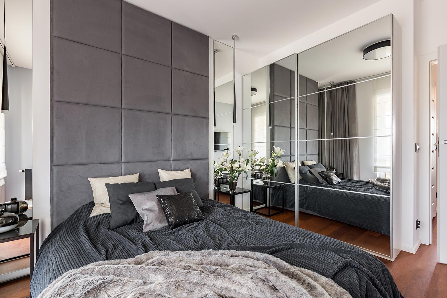 Luxurious bedroom with mirrored wardrobe, double bed and upholstered wall