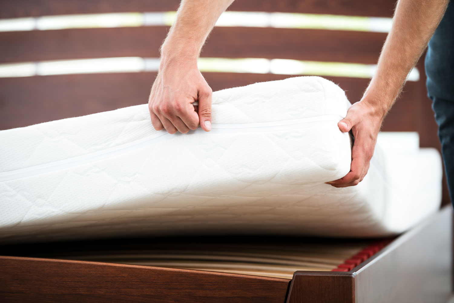 Man placing a mattress on the wooden bed