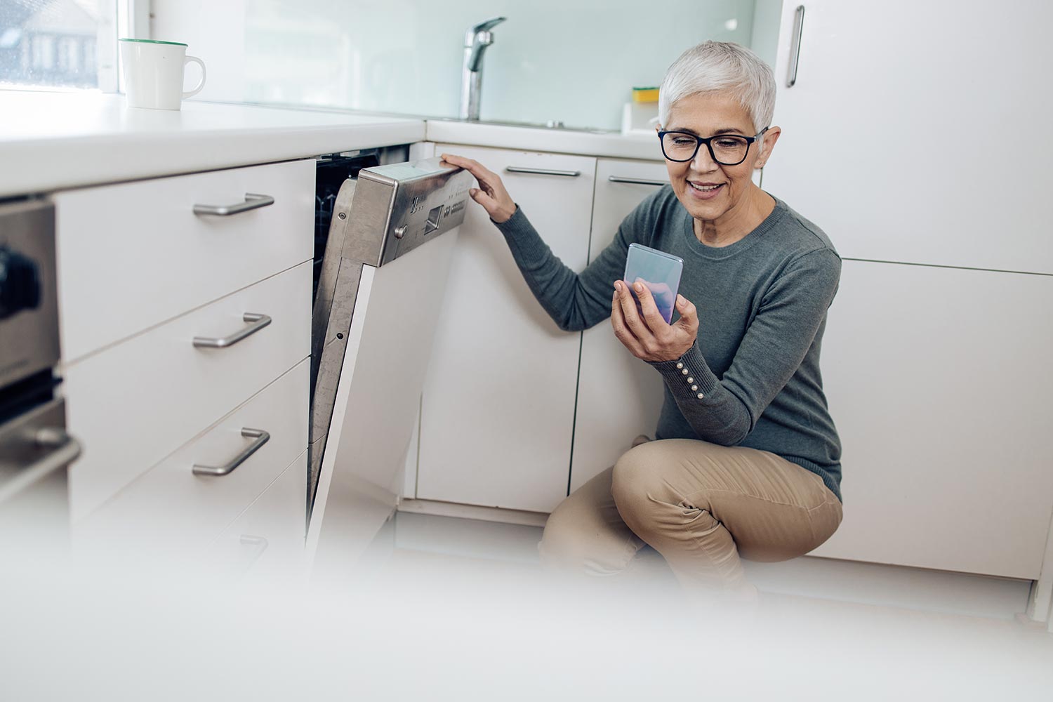 Mature woman checking an online tutorial before turning on her dishwasher