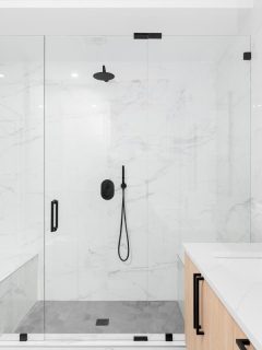 Modern bathroom with a light wood cabinet, walk-in shower with marble tiled walls, and black faucets and hardware, 11 Gorgeous Bathrooms With Black Fixtures