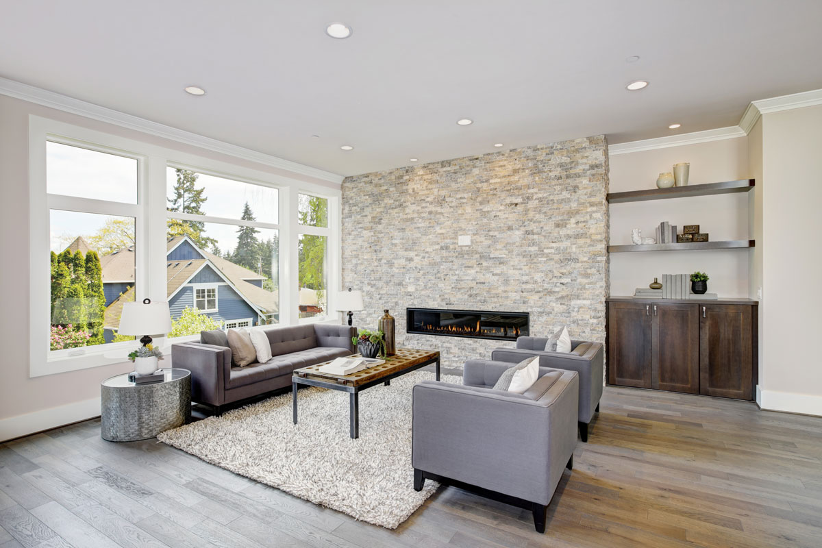Modern great room features a floor to ceiling stone fireplace