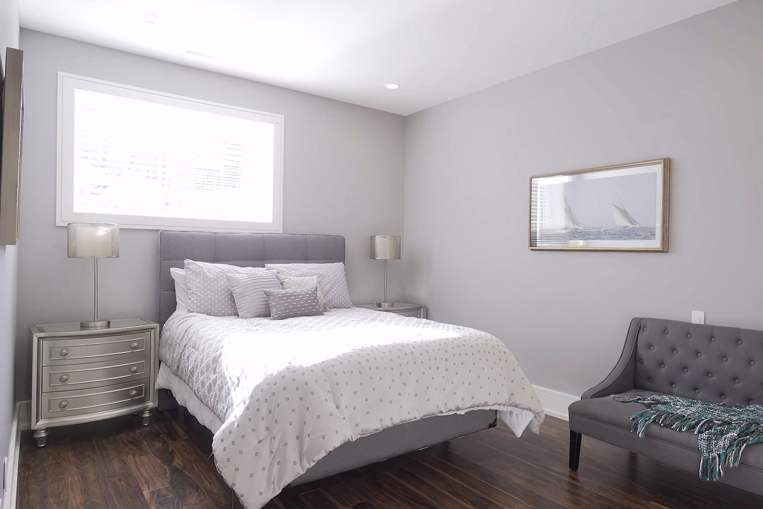Narrow bedroom with gray painted walls, wooden flooring and white polka dotted beddings