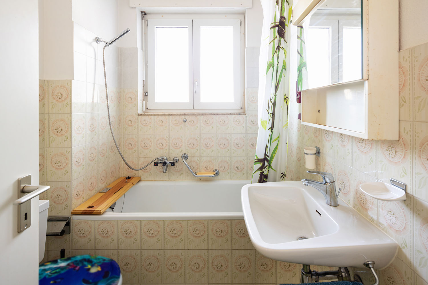Narrow modern bathroom with patterned tiles with a floral shower curtain