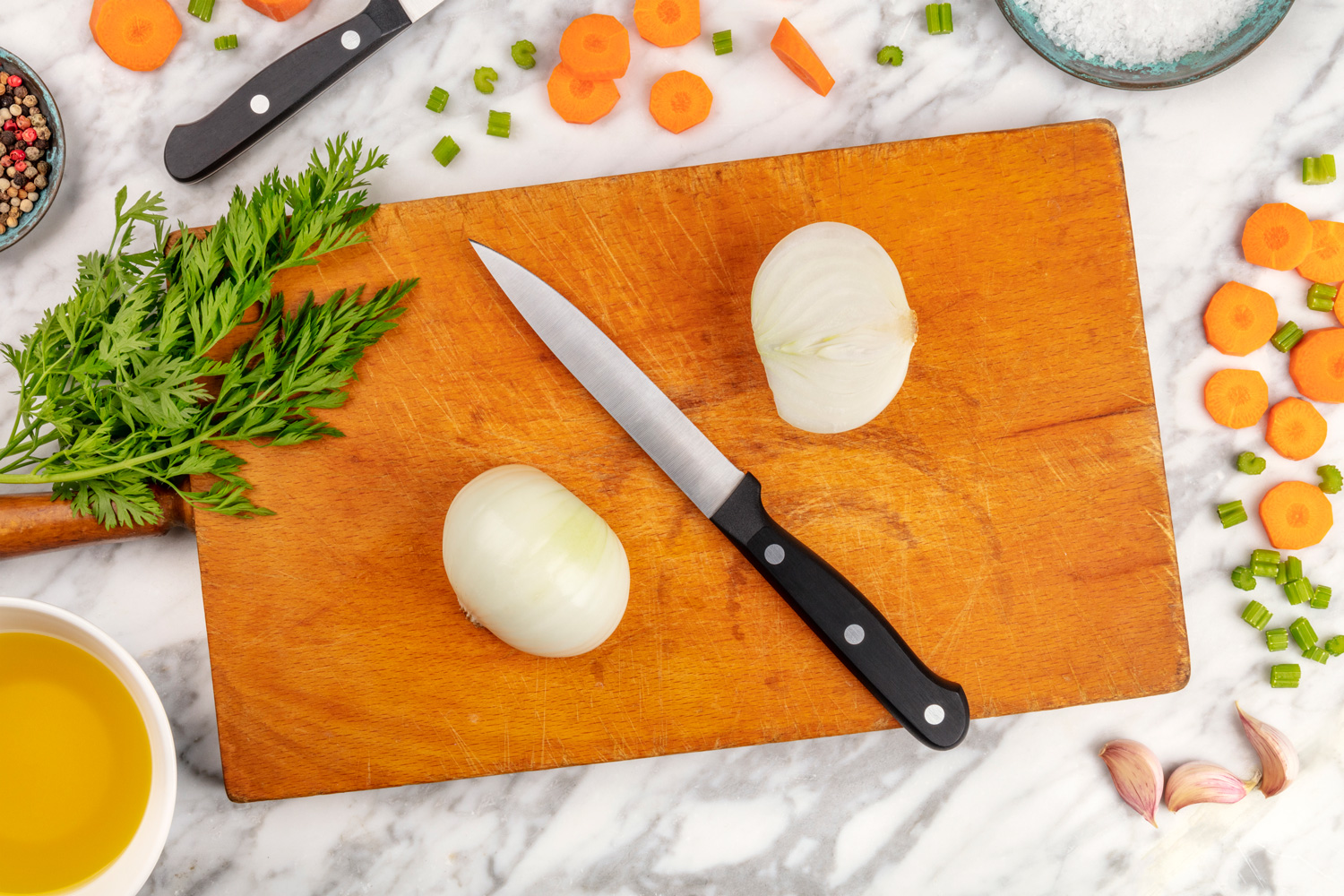 Prep time, or mise en place. An overhead photo of a professional chef's knive, shot from above on a cutting board, with chopped vegetables and spices, on a marble cooking surface