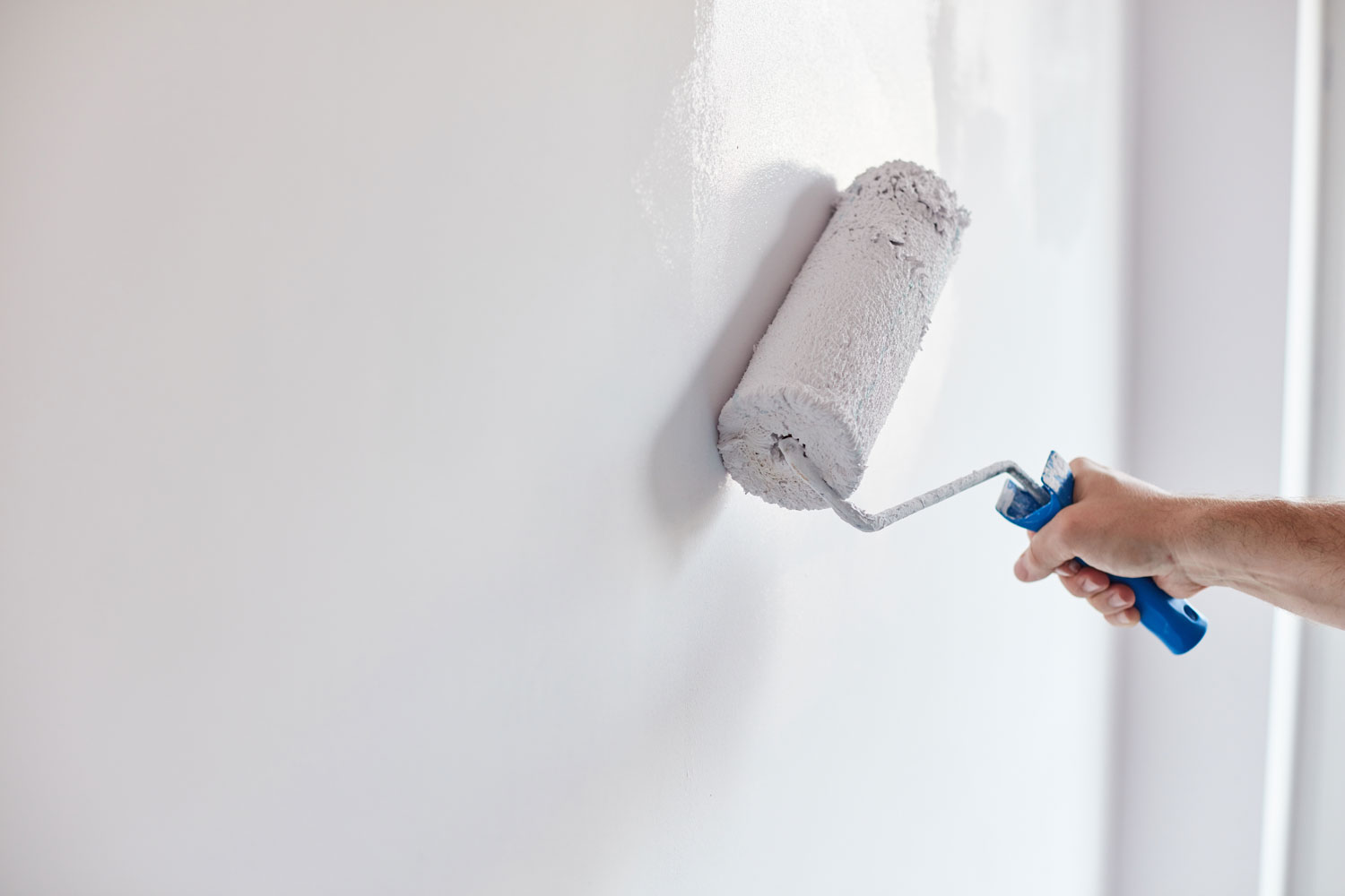 Painting the wall with white using a roller paint