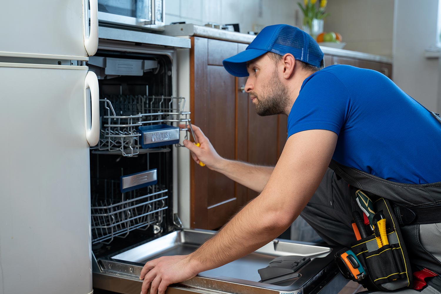 Repairman repairing dishwasher in kitchen