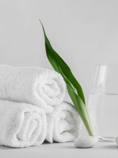 Spa setting decorated with green leave towel and white stone, What Color Towels For A Beige Bathroom? [6 Great Ideas!]