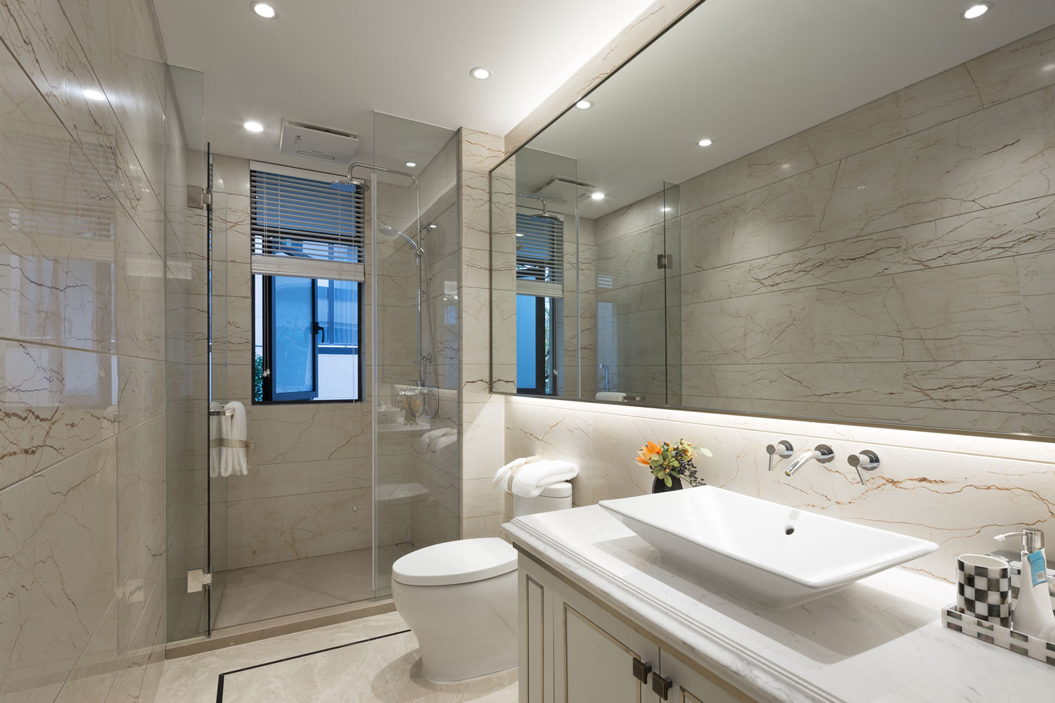 Vanity with a huge mirror and white cabinet with a glass wall shower