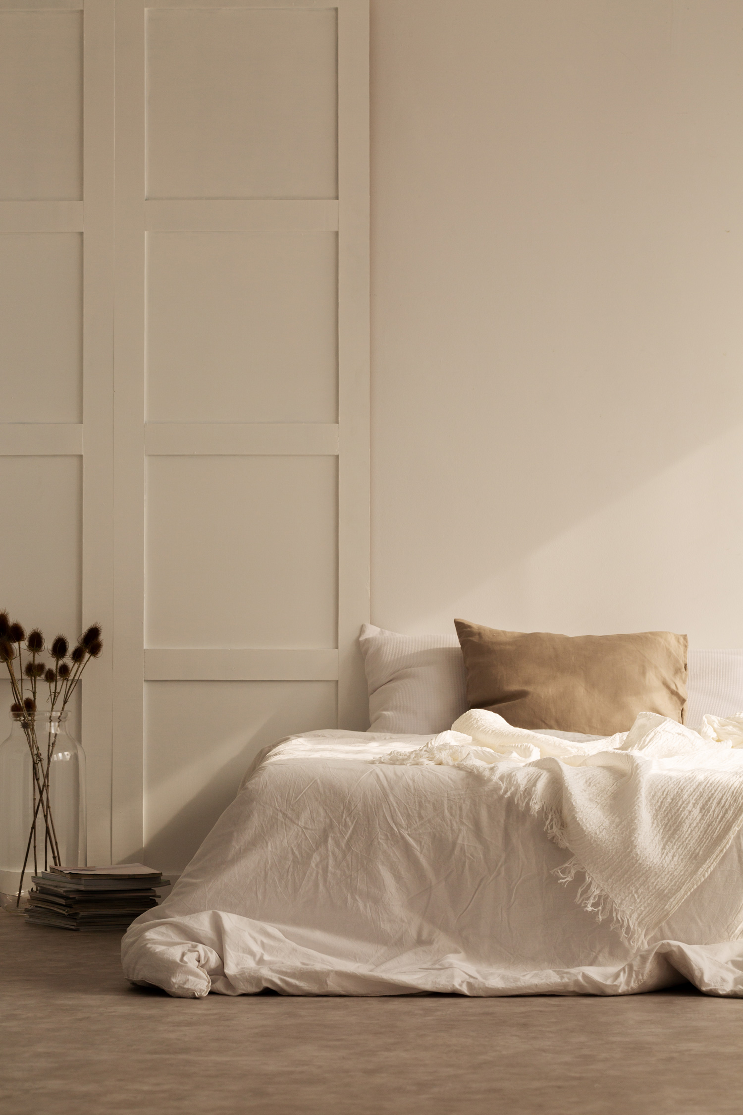 Vertical view of linen pillow on the bed in white bedroom of stylish house, real photo