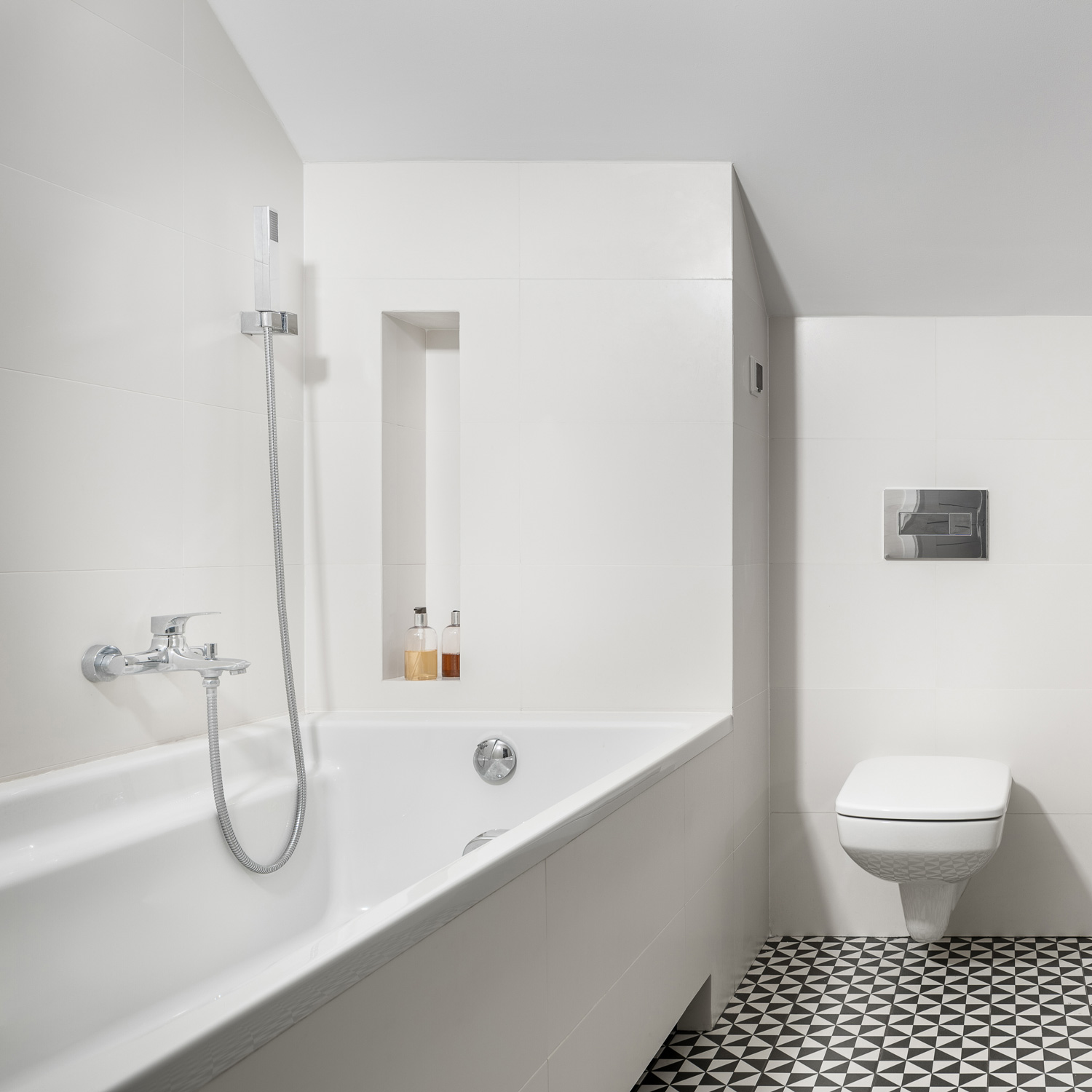 White bathroom with bathtub, toilet and black and white mosaic floor tiles