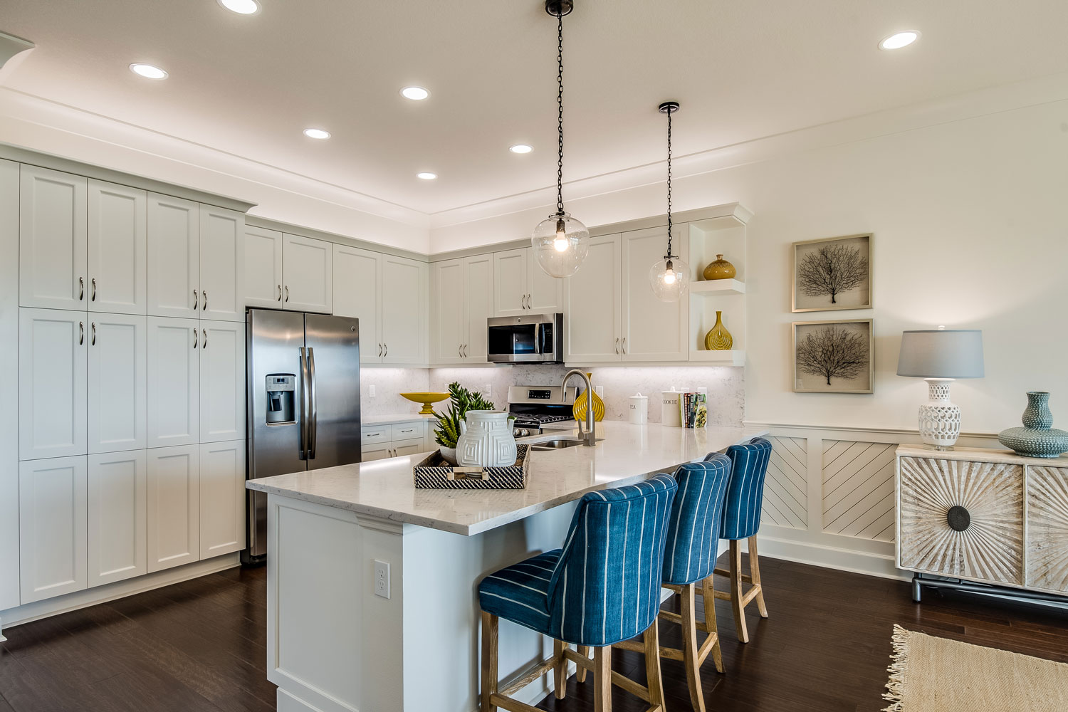 White overall kitchen design with white cabinets, white marble countertop and breakfast bar and dangling lamps