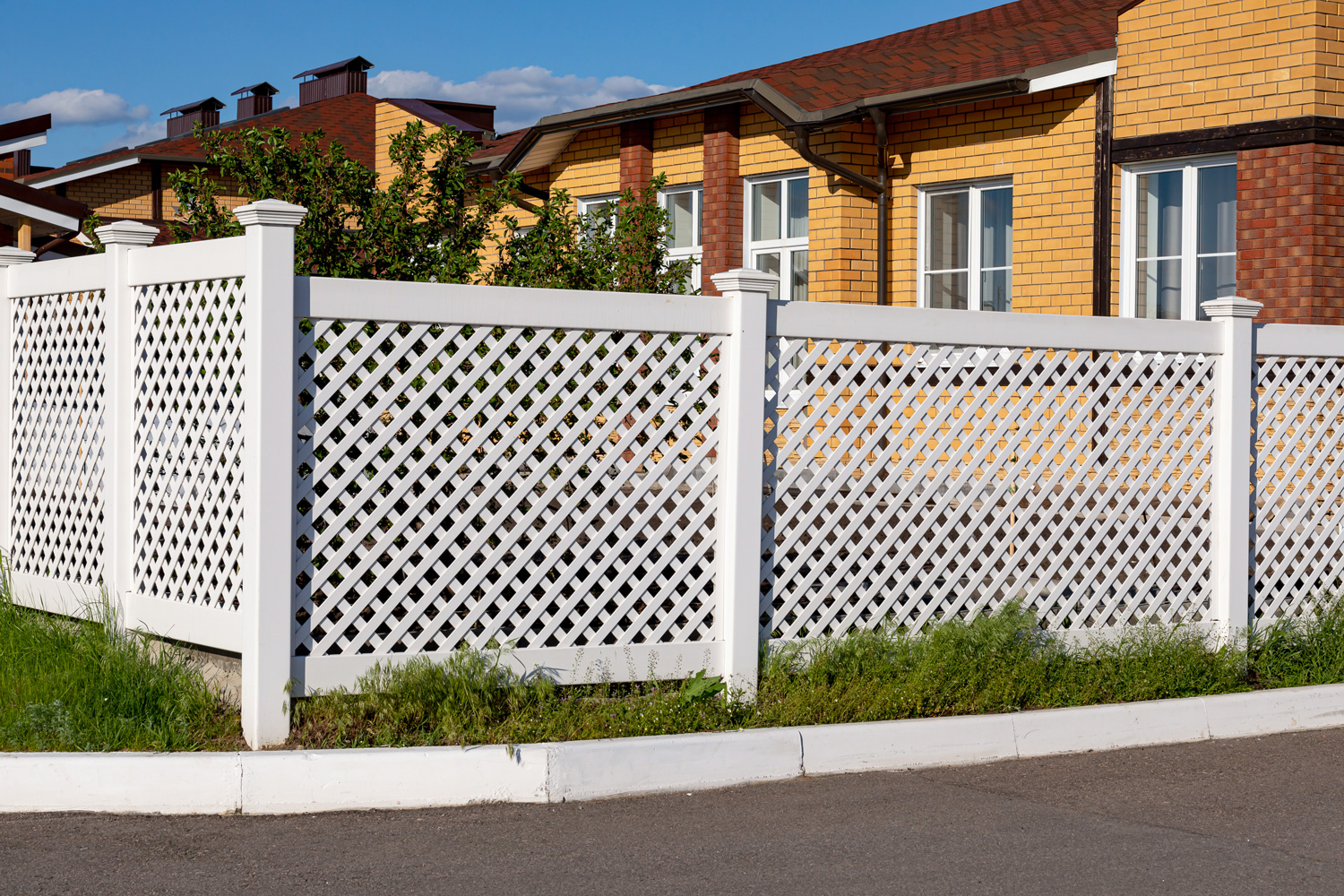 White plastic fence around a house in a cottage village. Concept of landscaping, protection, fencing of a territory