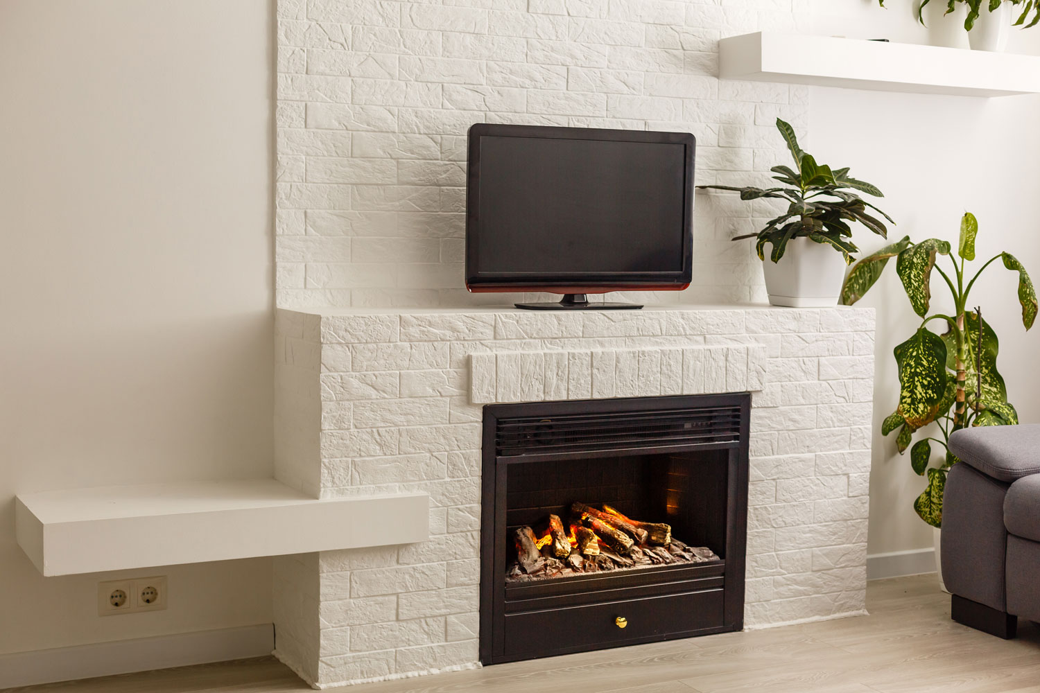White stone cladding on the fireplace with a TV on the fireplace mantel