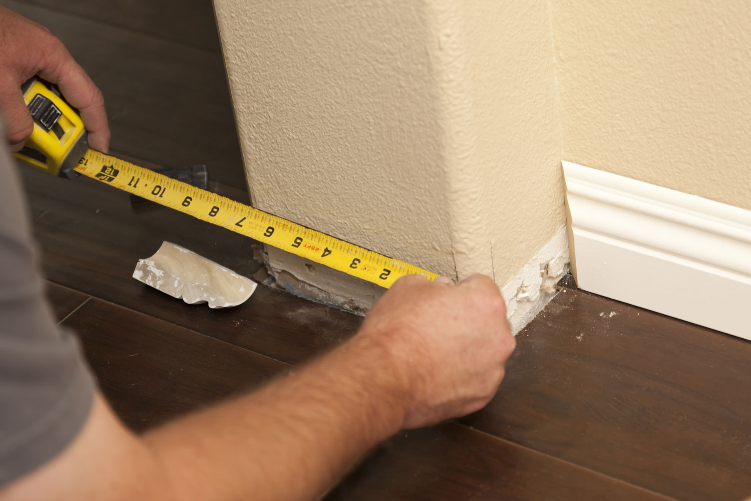 Worker measuring the side of the wall for baseboard