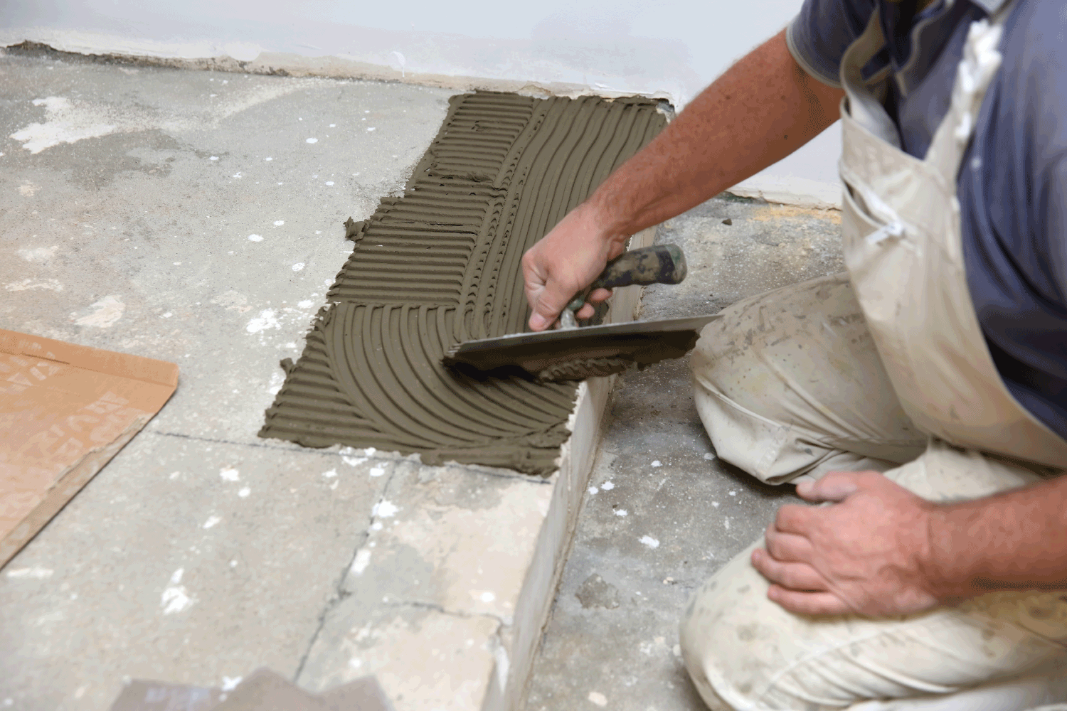 construction worker uses a cemented trowel to apply cement glue to the stairs