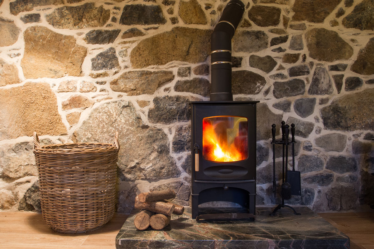 interior and hearth of a stone walled cottage with a wood burner fireplace